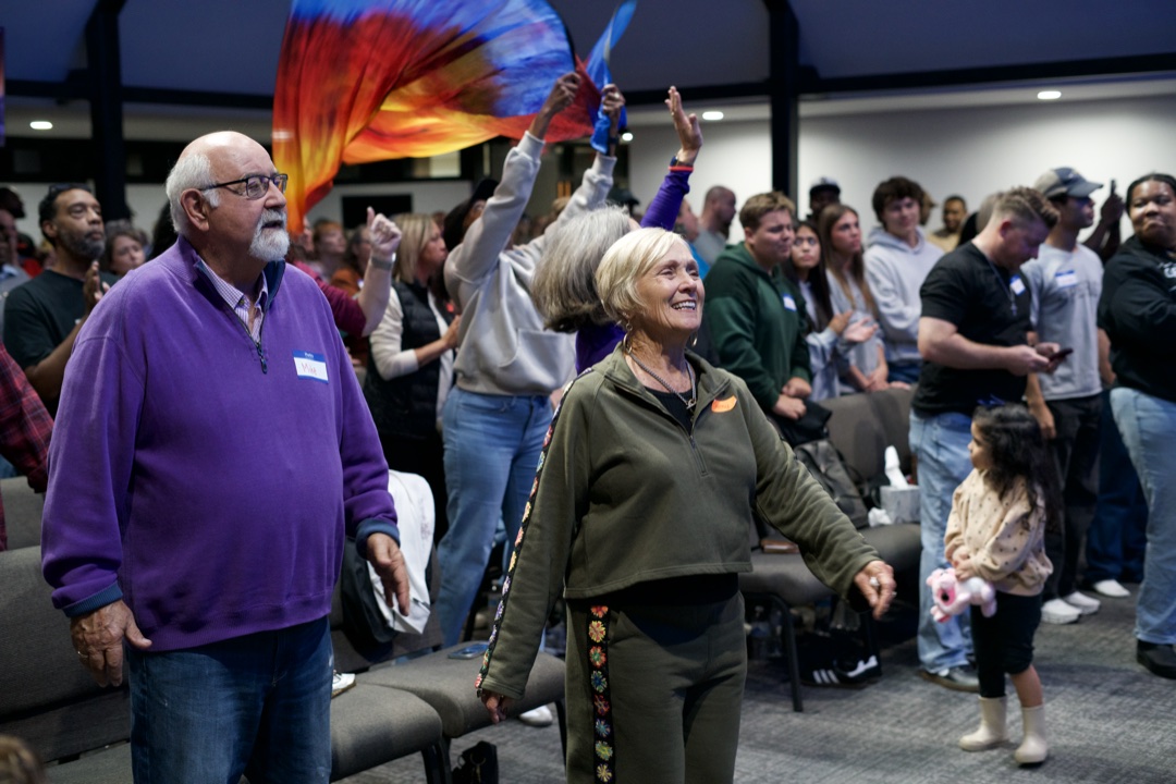 Grandparents, kids and young adults worshipping together, with flags waving